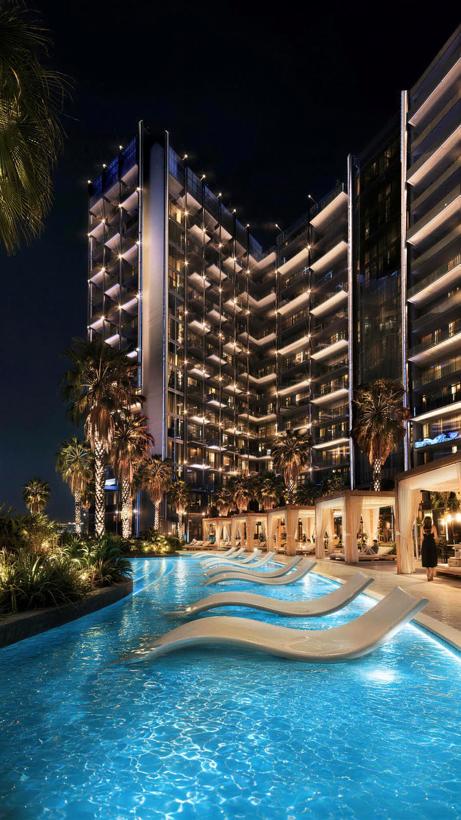 Infinity-Pool mit Loungern vor dem beleuchteten Turm